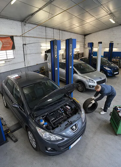 Mécanicien inspectant moteur Peugeot en atelier équipé de relevages.