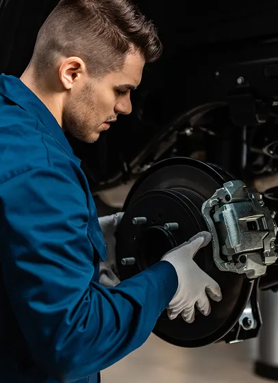 Mécanicien inspectant un disque de frein sur véhicule Peugeot en atelier.