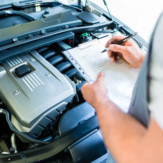 Mécanicien notant une intervention sur moteur Peugeot ouvert.
